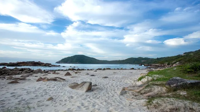 Praia com pedras e céu nublado em Garopaba